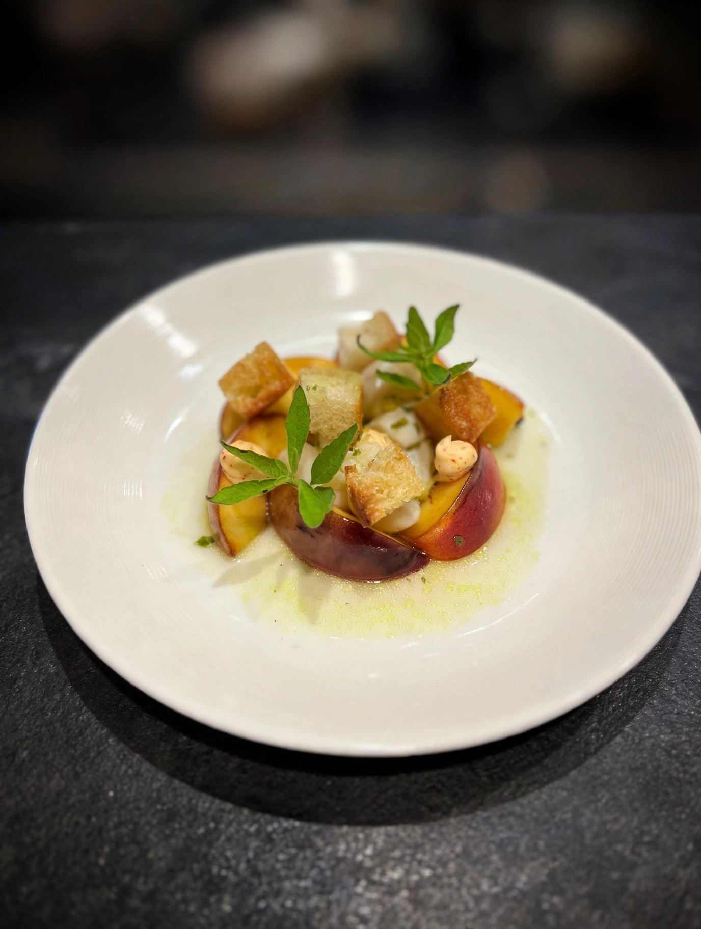 Crudo de pétoncle et pêche dressé en assiette